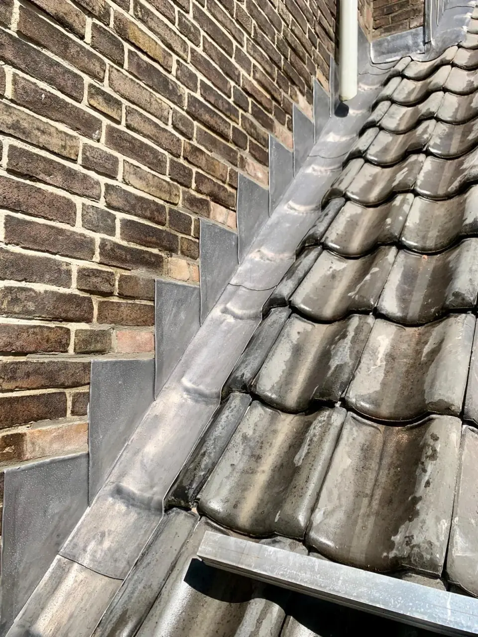Wandaansluiting boven grijze dakpannen