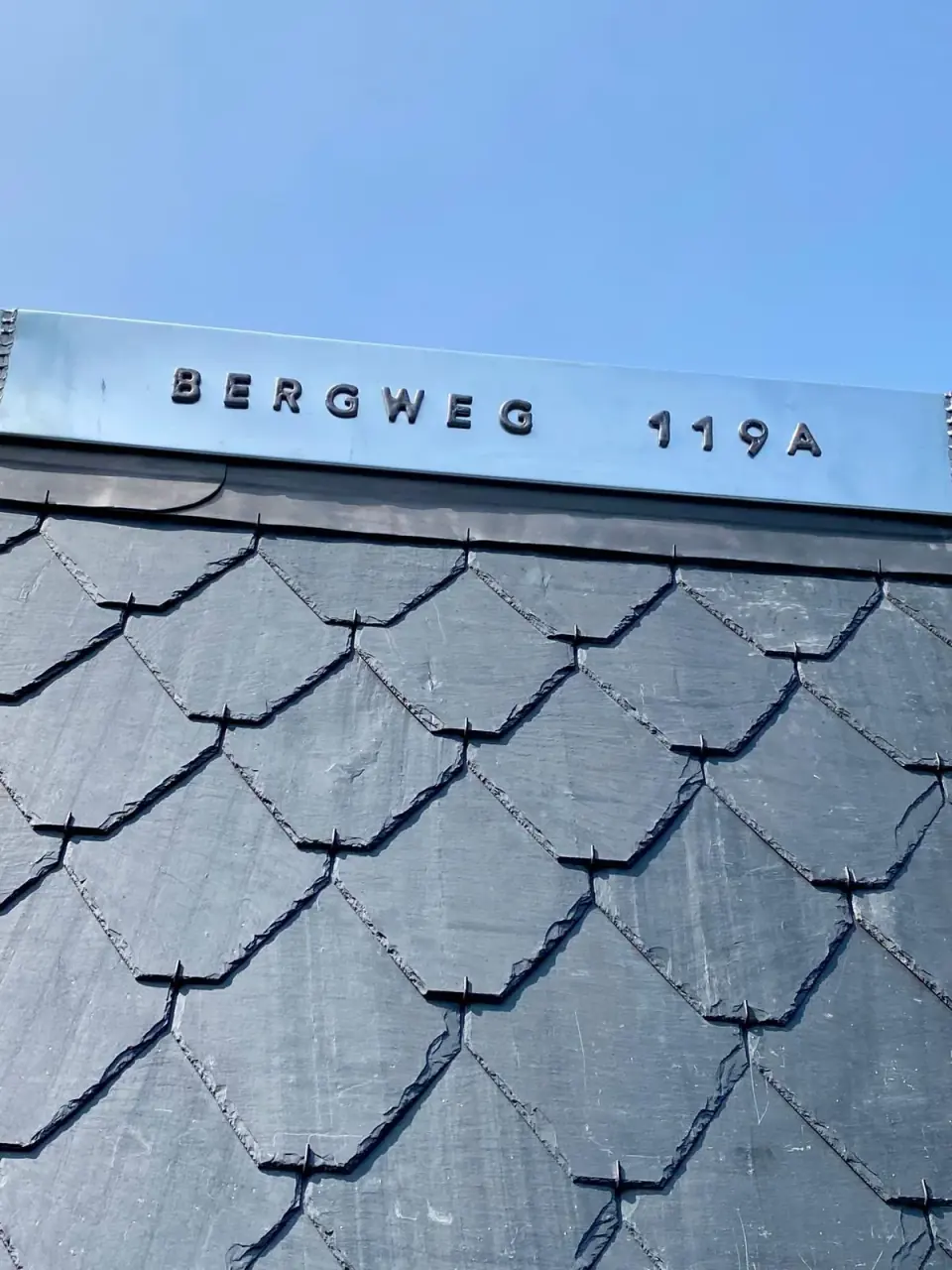 Metalen belettering boven geschubde leien