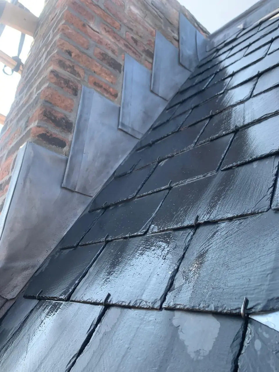 Loodslabben langs metselwerk bij een leien dak