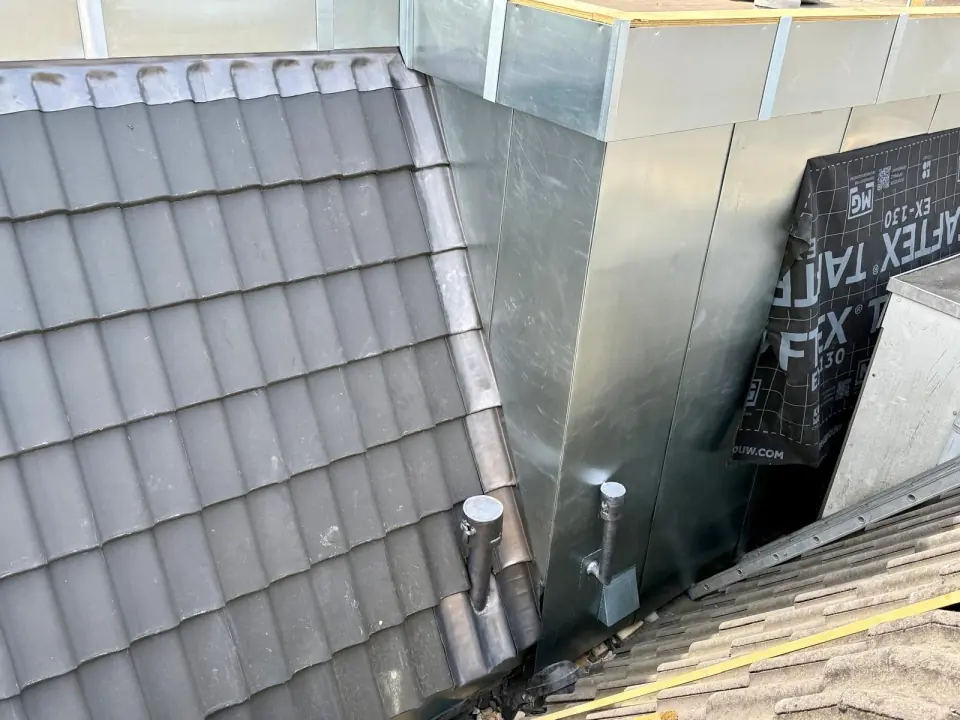 Metalen dakkapelzijwand naast grijze pannen