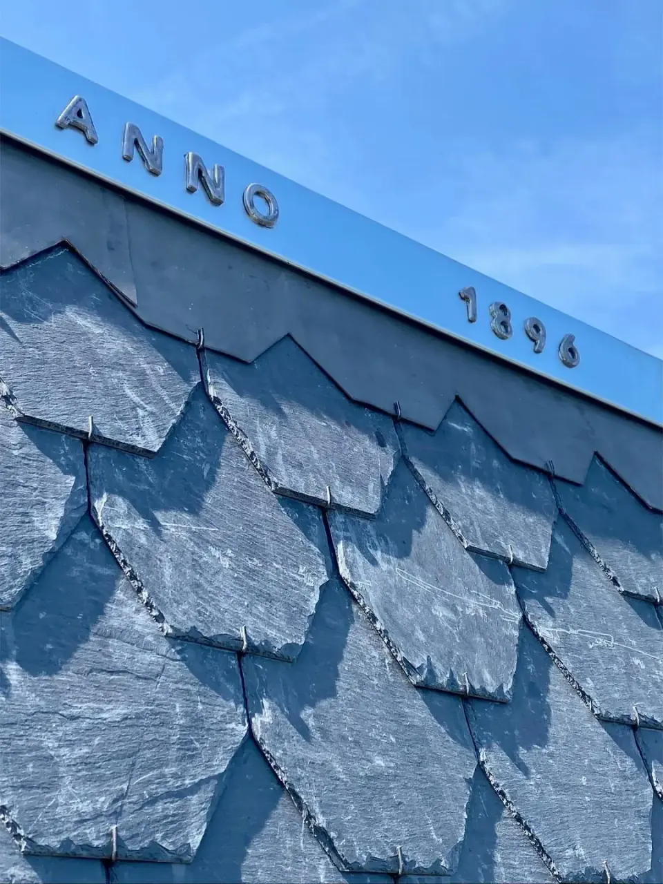 Geschubde leien onder een metalen afwerking met de letters ANNO 1896