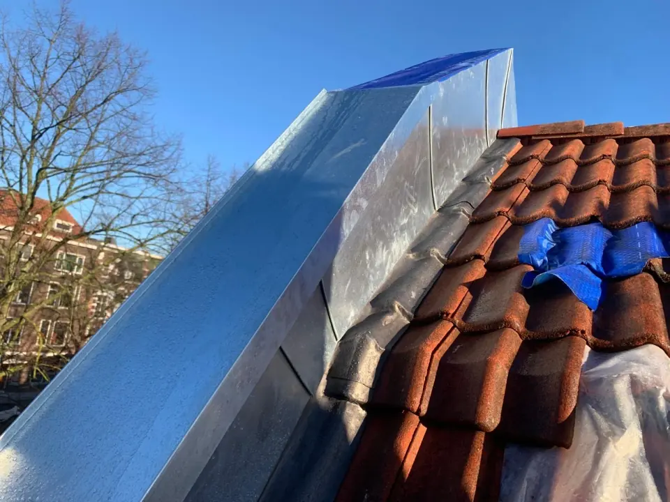 Metalen slabbe naast rode dakpannen